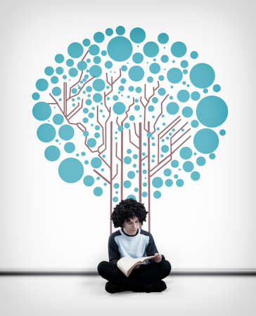 Young man reading a book in front of a white wall drawn with a circuit board tree.