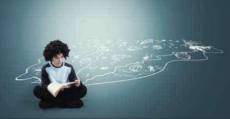 Teenager reading a book next to a drawn suggesting imagination chaotic and creative world - Image