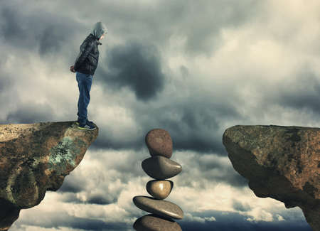 Kid standing at edge of a mountain peak looking down.の写真素材