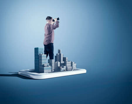 Man looking through binoculars in a city on a smartphone.の写真素材