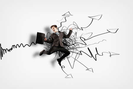 Businessman jumping in front of drawn wall with arrows leading to different directions. The concept of variety of choicesの写真素材