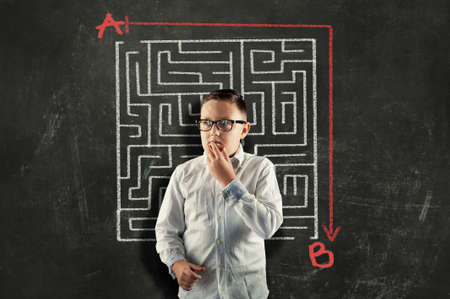 Kid solving a maze using a shortcut. Maze drawn on blackboard .