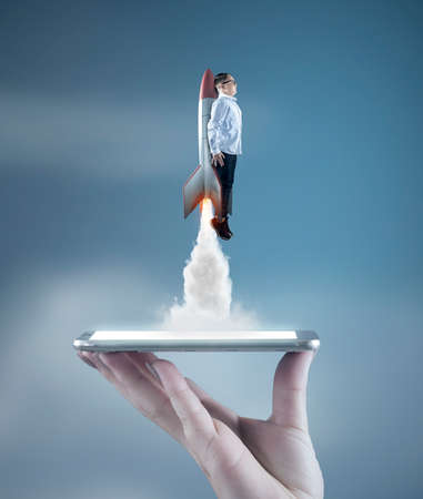 Young businessman take off with a rocket over a smartphone. Launch start up business online .の写真素材