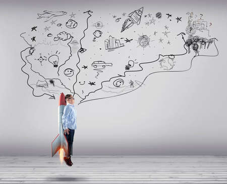 Young businessman rising up with a rocket next to wall drawn . Chase the dream concept.の写真素材