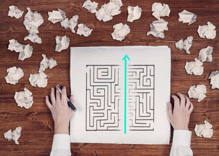 Shortcut of a maze drawn on paper . Crumpled papers arround. Easy solution of a difficult problem.