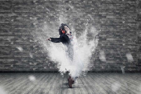 Woman listening music on headphones and dancing . Powder explosion motion dance .の写真素材