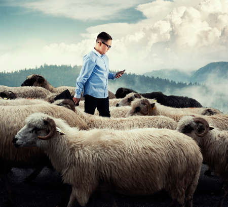 Businessman standing in the middle flock of sheep walking in opposite direction. Out of the box concept. Stand out from the crowd.の写真素材