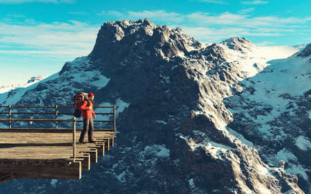 Hiker with backpack standing on a bridge in front of a mountain during winter . This is a 3d render illustration .の写真素材