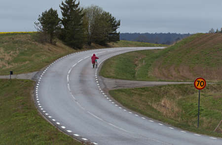 Female cyclist who leads his bike uphillの写真素材