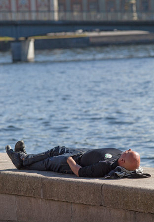 STOCKHOLM SEPTEMBER 03 2014.  Resting man on stone wall in the center of Stockholm.のeditorial素材