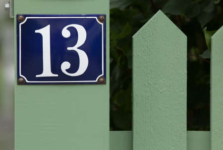 House number thirteen on green fenceの写真素材