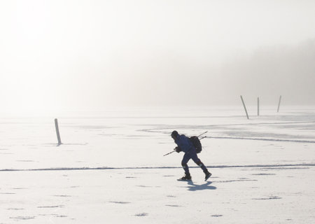 SWEDEN Jan 19 2016. A man on skates on a frozen sea.  The bright dots that are clearly visible against the man's clothes are snow and ice crystals that form in the air in backlight.のeditorial素材