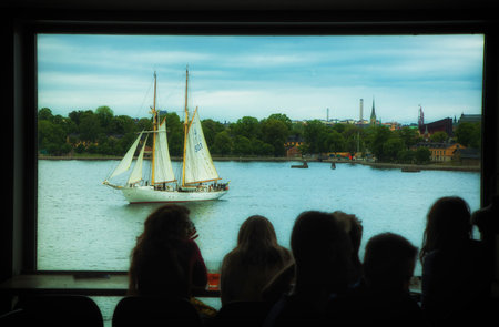 STOCKHOLM SWEDEN 4 JUNE 2017. Sailing boat Gladan in Stockholm. People sitting at a large window at the Photographic Museum in Stockholm.のeditorial素材