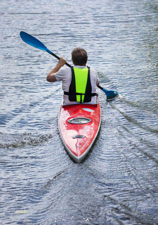  A man paddles a red canoe in Stockholm city.