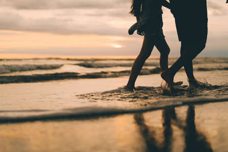 A young couple walking bearfoot in the ocen's waves easily and relaxing. Perfectly for text.の写真素材