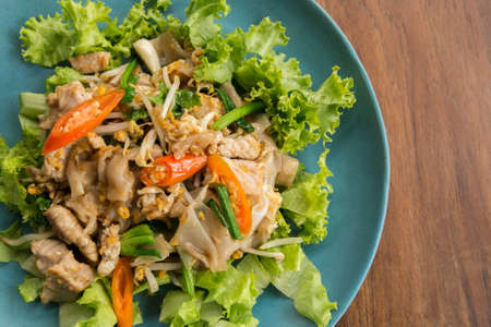 Stir fried Flat Rice Noodle with Soy Sauce and Pork 'Pad See Eww' on wooden table - Thai street foodの写真素材