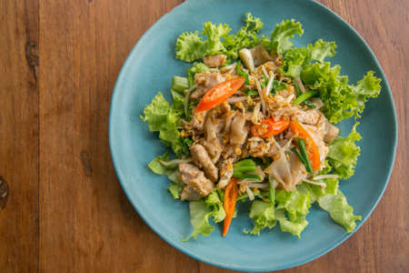 Stir fried Flat Rice Noodle with Soy Sauce and Pork 'Pad See Eww' on wooden table - Thai street foodの写真素材