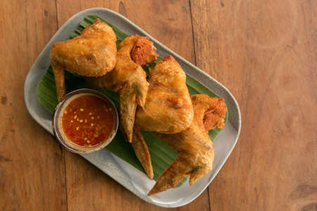 Deep fried chicken wings crispy and delicious thai sweet sauce on a wood tableの写真素材