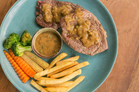 Pork steak, french fries, and vegetable on a wooden table - Western foodの写真素材
