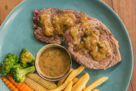 Pork steak, french fries, and vegetable on a wooden table - Western foodの写真素材