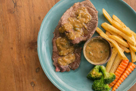 Pork steak, french fries, and vegetable on a wooden table - Western foodの写真素材