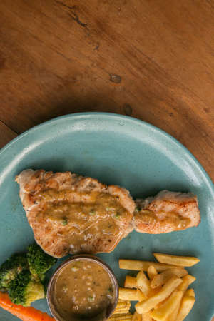 pork steak, french fries, and vegetable on a wooden table - Western foodの写真素材