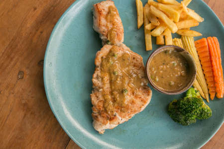 pork steak, french fries, and vegetable on a wooden table - Western foodの写真素材