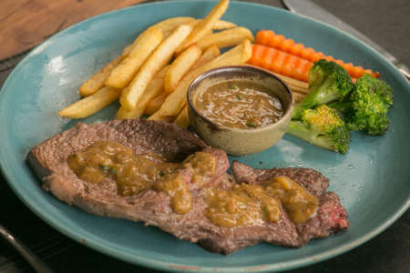 Pork steak, french fries, and vegetable on a wooden table - Western foodの写真素材