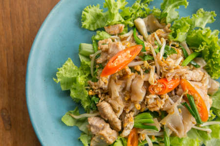 Stir fried Flat Rice Noodle with Soy Sauce and Pork 'Pad See Eww' on wooden table - Thai street foodの写真素材