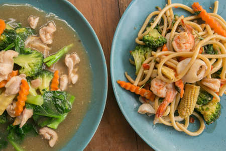 Thai Street food. Thai fried noodles with chicken in Thai style gravy. ("Rad Nha Seafood") and Spaghetti with spicy seafood asian styleの写真素材