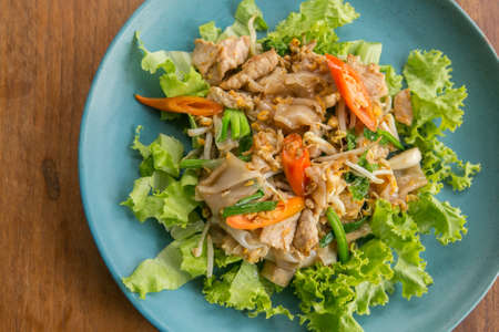 Stir fried Flat Rice Noodle with Soy Sauce and Pork 'Pad See Eww' on wooden table - Thai street foodの写真素材