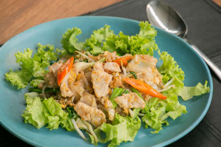 Stir fried Flat Rice Noodle with Soy Sauce and Pork 'Pad See Eww' on wooden table - Thai street foodの写真素材