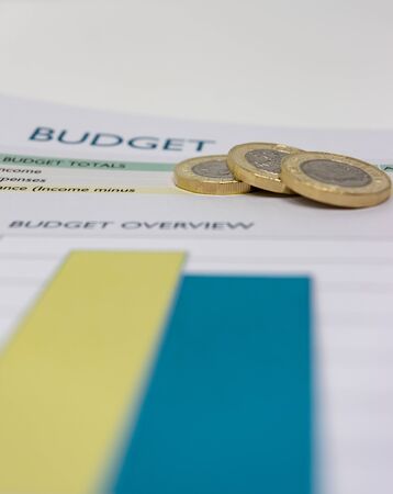 Budget sheet with pound coins on top.の写真素材
