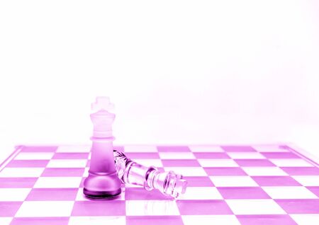 Two King chess pieces on a board in pinkの写真素材