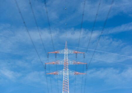 Straight veiw od a red and white electricity pylon with a blue sky background.の写真素材