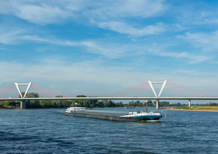 Dusseldorf, Rhineland, Germany, 09/15/2019 - ship passing Airport suspension bridge on a sunny day with blue sky.のeditorial素材