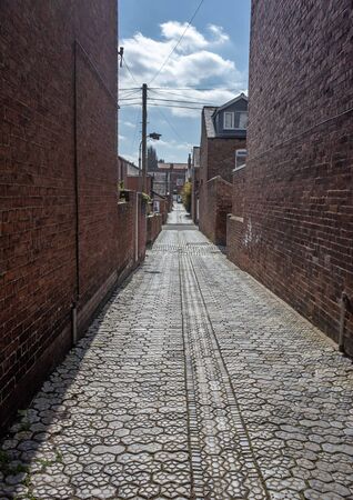 A cobbled allyway between red bricked buildings, leading into the distance.の写真素材