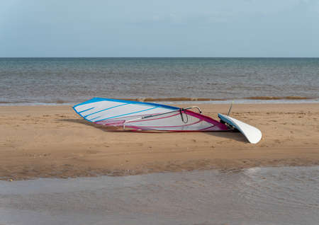 A single wind surfing board on a sandy beach with the sea in backgroundの写真素材