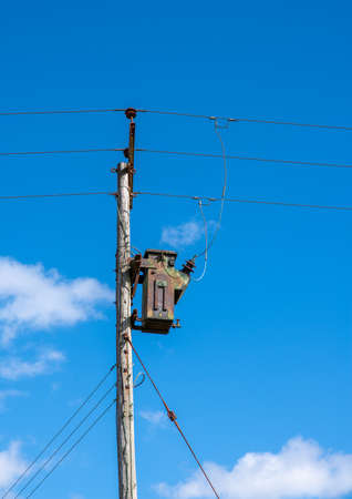 Telegraph pole style pylon with an electrical transformer with a cloudy sky backgroundの写真素材