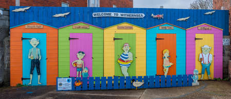 Withernsea, East Yorkshire, England, 20/10/2020 - five colorful painted beach huts with holiday makers in doorways.のeditorial素材
