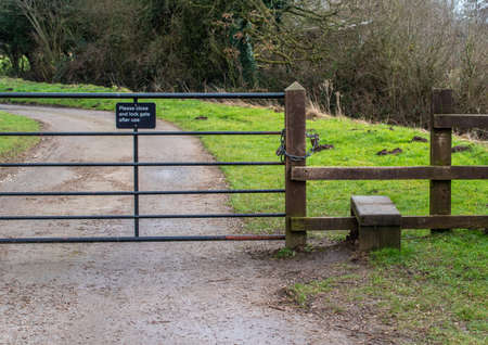 Please close the gate sign on a metal gate with a wooden fence style.の写真素材