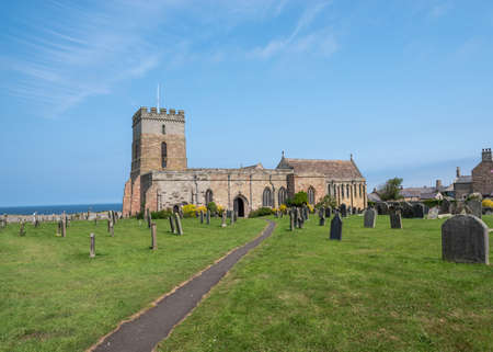 Bamburgh, Northumberland, UK, 21 July 2021 - St Aidens Church and graveyard on sunny day with blue sky.のeditorial素材