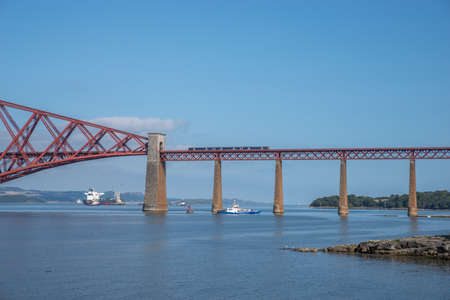 South Queensferry, Edinburgh, Scotland 7th September 2021 - View of a Scotrail Train on the Forth Rail Bridge with a Ferry below on a sunny day.のeditorial素材