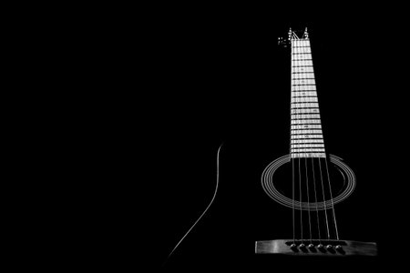 the guitar is black acoustic on a black background, silhouette. black and white, close-up, front...