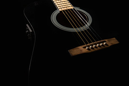 black electro-acoustic guitar on a black background, silhouette, close-up, front side view
