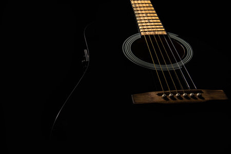 the guitar is black acoustic on a black background, silhouette. close-up, front view from below