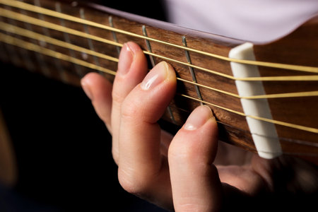 playing guitar, hand clenching a chord, learning music. lifestyle, close-up.