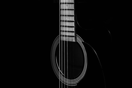 black acoustic guitar on a black background, silhouette. black and white, close-up, front side view