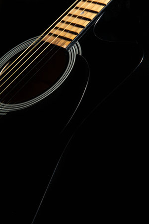 black acoustic guitar on a black background, silhouette. close-up, front-side view