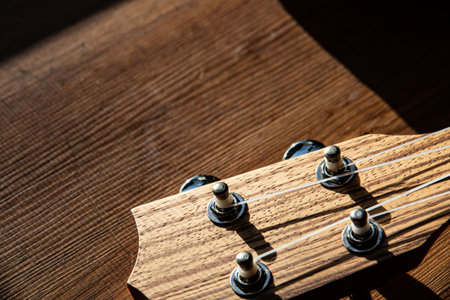 ukulele on a wooden background, head, headstock, lifestyle, rays of the sun. close-up, guitar...